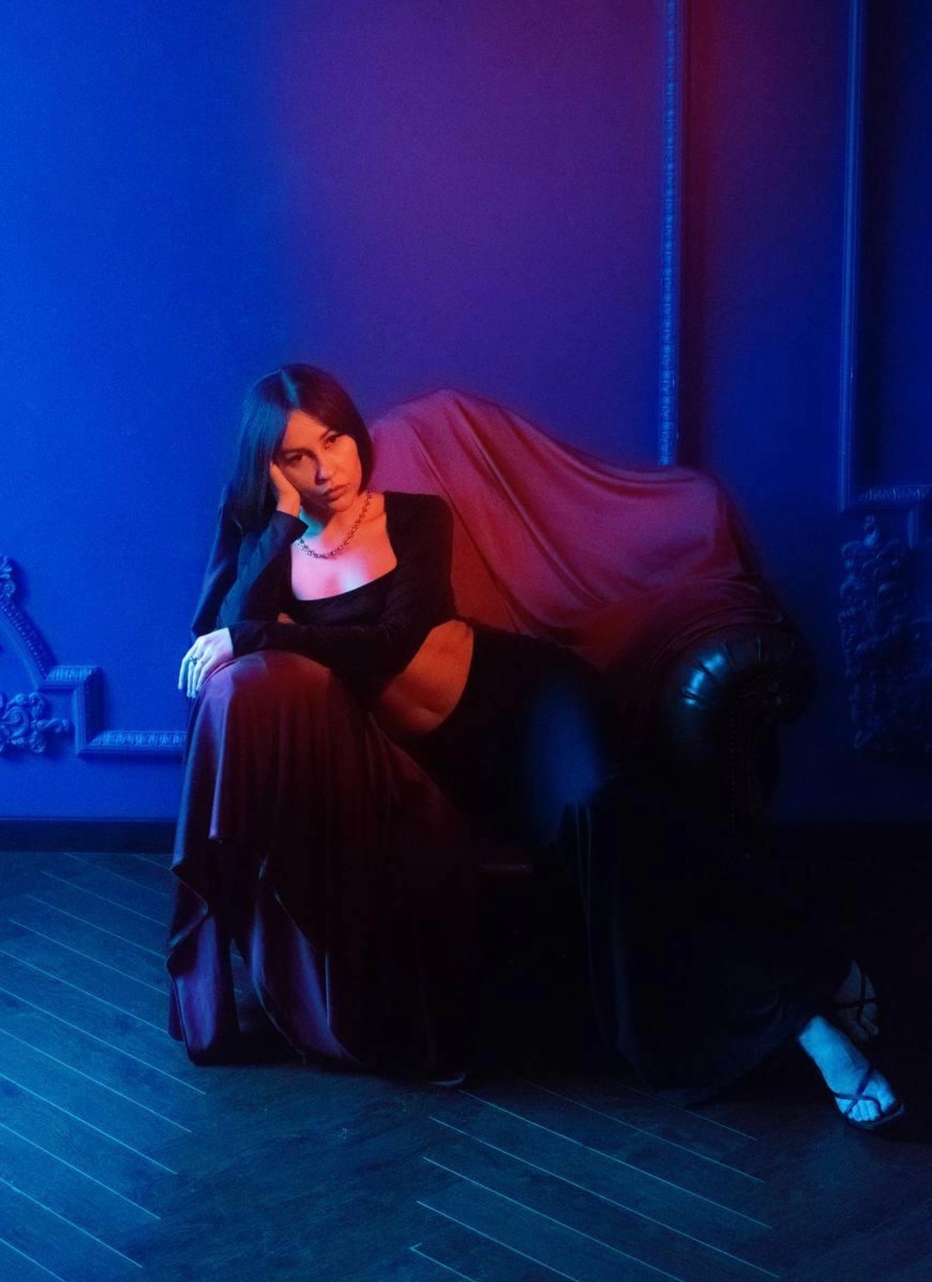 Artist seated in a blue and magenta-lit lounge